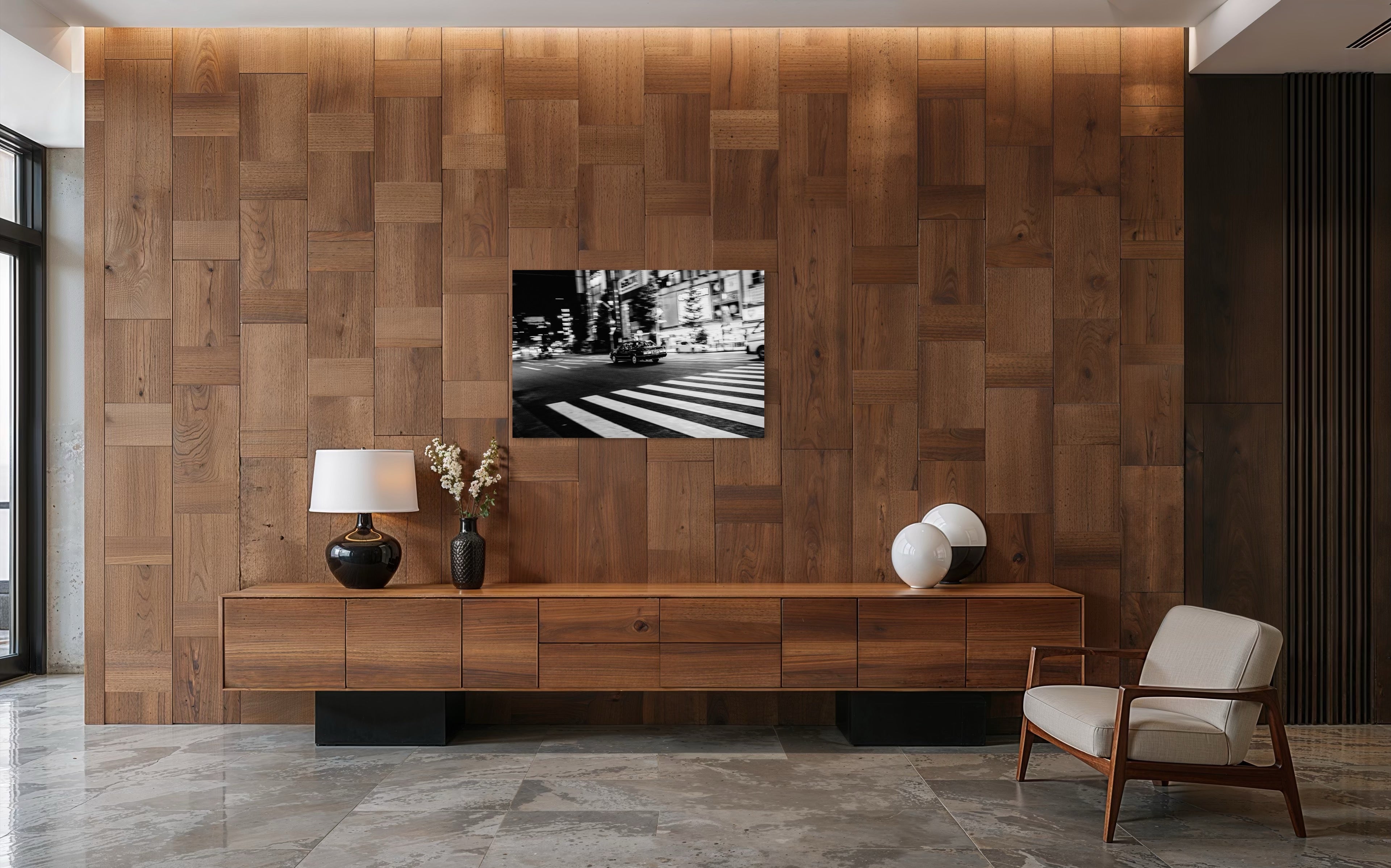 Der Schwarz-Weiss Fine Art Print "Just got it" zeigt eine nächtliche Tokyoter Strassenszene mit schwarzem Auto, hellem Stadtlicht und urbanem Nachtleben und hängt in einem modernen Wohnzimmer mit brauner Holz Wand und einem hellen Sessel.