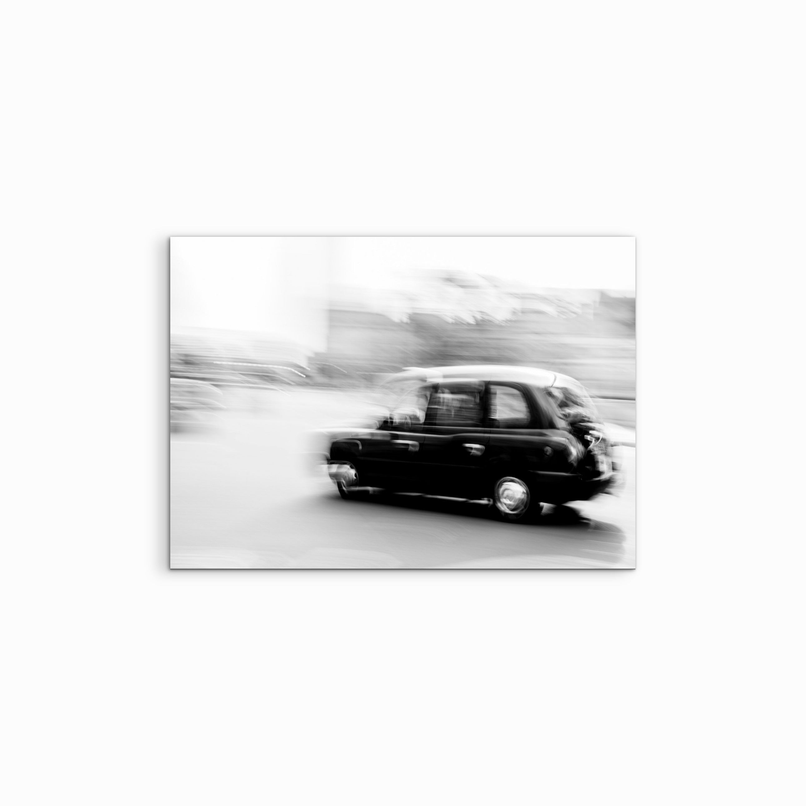 Fine Art Print „Churchill“ auf weissem Hintergrund, schwarz-weiss London Taxi im dynamischen Panning Shot, verzerrt und dennoch klar erkennbar, urbanes London Motiv mit Bewegungsunschärfe, moderner Street Photography Look als hochwertige Wandkunst.